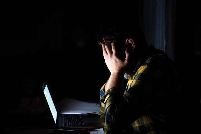 Homem usando o computador à noite no quarto, ilustrando a dúvida se pornografia vicia