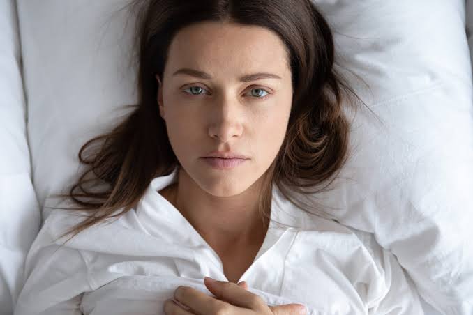 Pessoa deitada na cama, de olhos abertos, durante um episódio de paralisia do sono